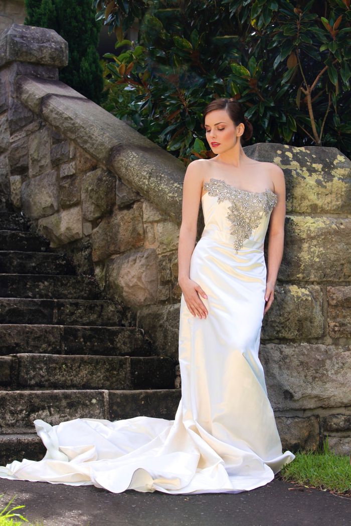 Contact A bride elegantly poses in a wedding dress by a stone staircase, exuding beauty and grace.