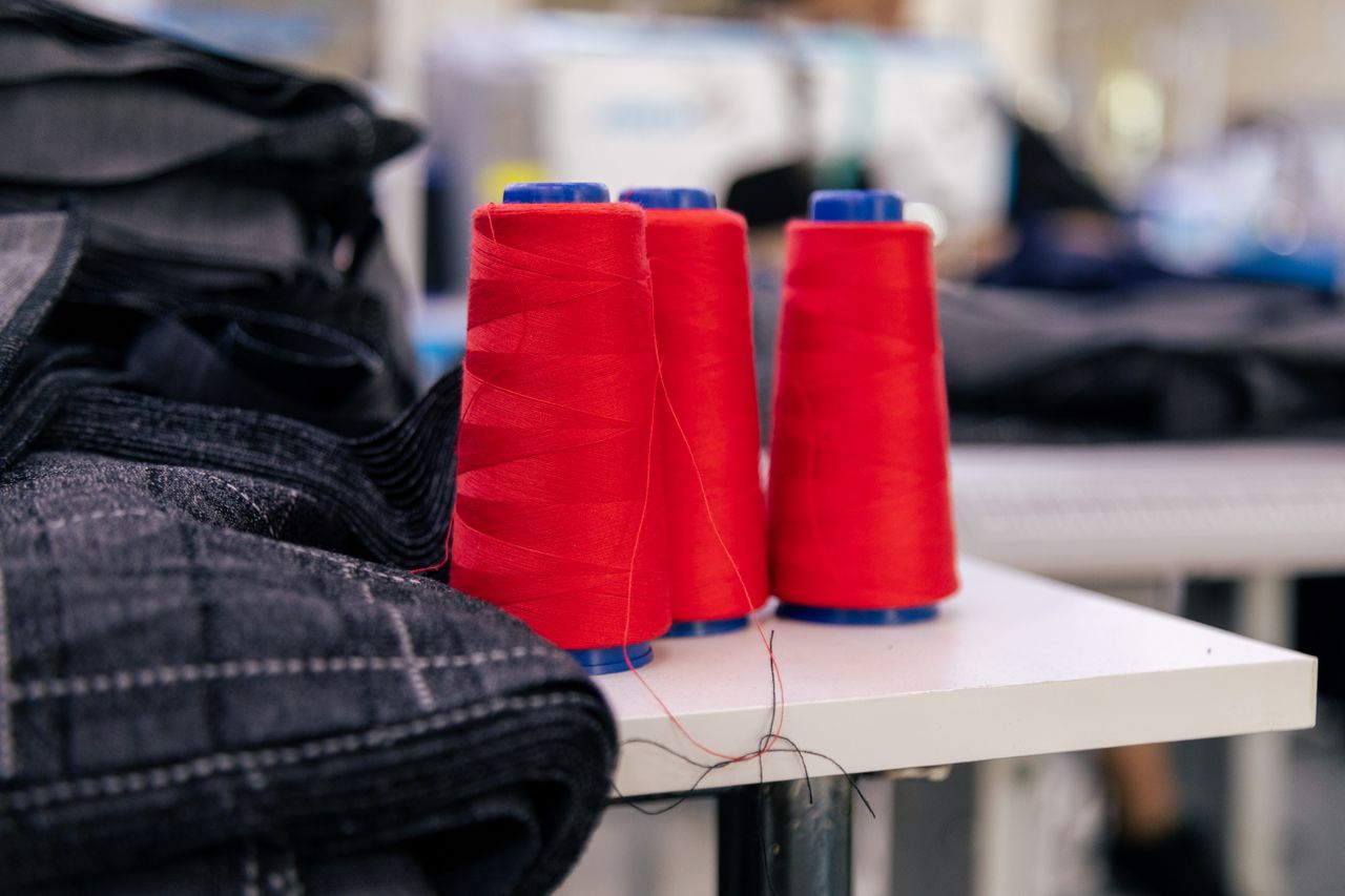 Contact Vibrant red thread spools on a table in a tailoring room. Ideal for sewing imagery.