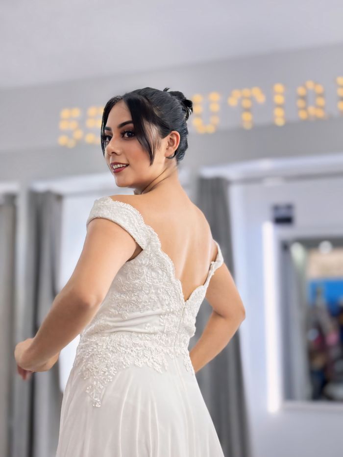 About Stylish bride posing in an elegant white wedding dress indoors with soft lighting.
