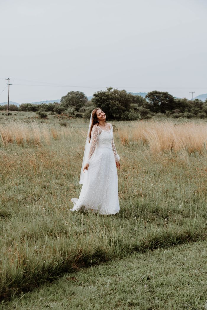 About A bride in a lace wedding dress enjoys a peaceful moment outdoors in a lush green field.